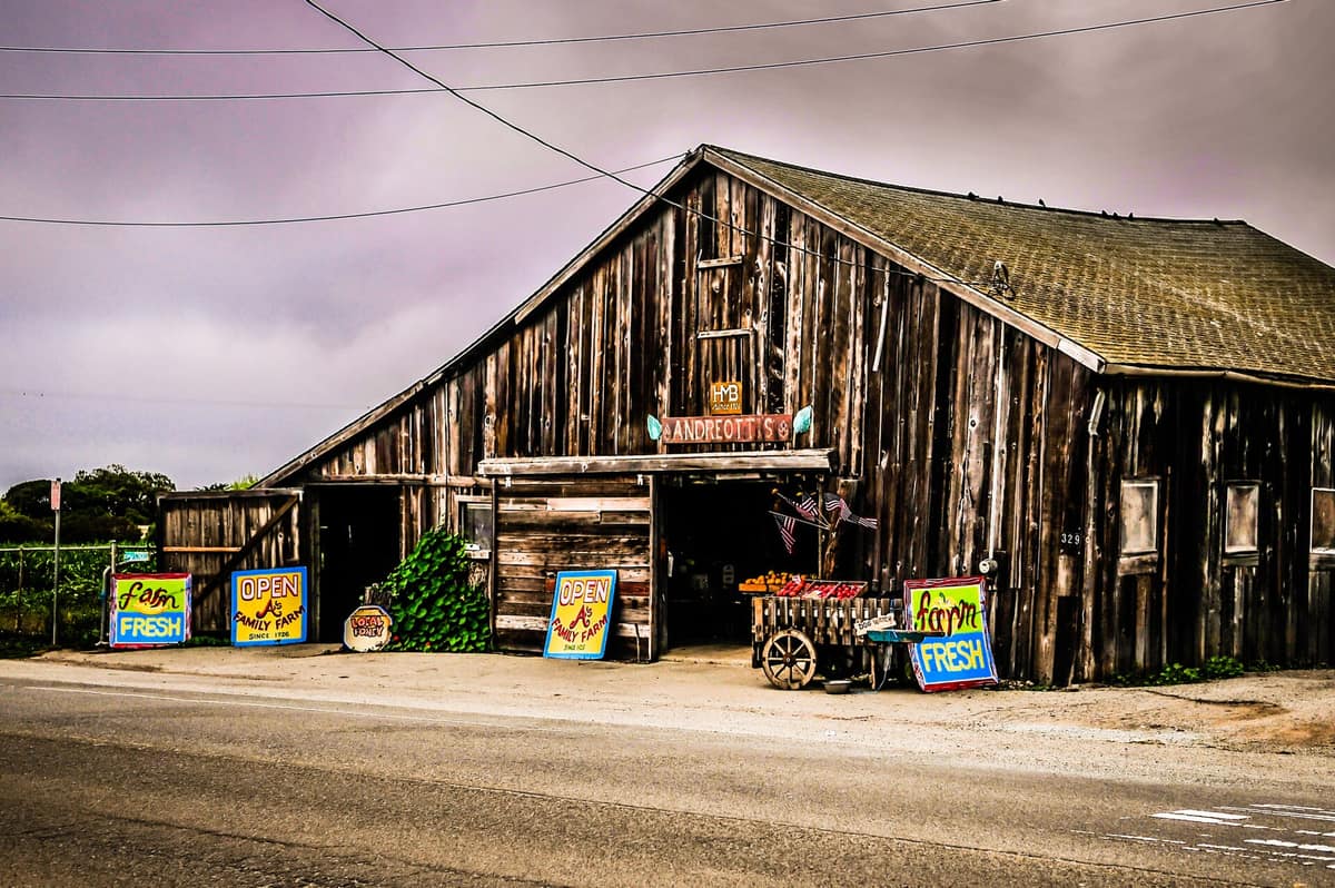 A weathered barn farm stand with hand-painted produce signs