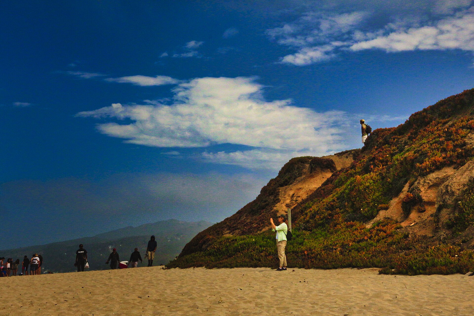 Beachgoers below a golden bluff on a clear day